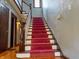 Elegant staircase with red carpet, wooden banister, and natural light at 333 N Kenyon St, Indianapolis, IN 46219