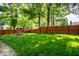 Beautiful backyard with a green lawn, mature trees, wood fence and fire pit area at 357 N Kenyon St, Indianapolis, IN 46219