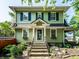 Charming two-story home featuring vibrant green siding, blue shutters, and a welcoming front porch and landscape at 357 N Kenyon St, Indianapolis, IN 46219