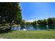 A serene lake view with lounge chairs on the dock, framed by lush greenery and a blue sky at 3829 Waycross Dr, Columbus, IN 47203