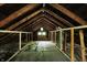 Unfinished attic with exposed wood beams and a small window at 5015 Carrollton Ave, Indianapolis, IN 46205