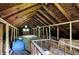 Unfinished attic with exposed wood beams and a small window at 5015 Carrollton Ave, Indianapolis, IN 46205