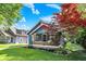 Charming blue home with a cozy front porch framed by a beautiful red tree and a lush green lawn at 5015 Carrollton Ave, Indianapolis, IN 46205