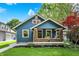 Charming blue home featuring a cozy front porch, manicured lawn, and vibrant landscaping, creating an inviting curb appeal at 5015 Carrollton Ave, Indianapolis, IN 46205