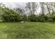 Large backyard featuring a cozy fire pit area nestled among mature trees and a lush green lawn at 5137 Green Hills Dr, Brownsburg, IN 46112