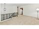 Neutral loft area with carpet, decorative railing, and view into the kitchen at 5225 Elderberry Rd, Noblesville, IN 46062