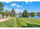 Manicured backyard with a pond view and mature trees on a sunny day at 5521 Salem N Dr, Carmel, IN 46033
