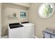 Bright laundry room with modern washer and dryer, shelving, and a round window at 5521 Salem N Dr, Carmel, IN 46033