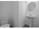 A powder room with a round mirror, sink, and toilet providing convenience for guests at 6219 Medina Spirit Dr, Indianapolis, IN 46237