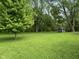 Spacious backyard with lush lawn and mature trees, featuring a screened porch for outdoor enjoyment at 7897 Moore Rd, Indianapolis, IN 46278