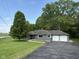 Ranch-style home with a two-car garage, mature tree and an asphalt driveway surrounded by a well-manicured lawn at 7897 Moore Rd, Indianapolis, IN 46278