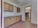 Vintage kitchen featuring wood cabinets, brick floor, and an adjacent room with a brick fireplace at 8903 Maple Hill Dr, Indianapolis, IN 46239