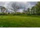 An expansive green backyard beneath a cloudy sky, surrounded by lush trees, offering a serene and private outdoor space at 8944 W 21St St, Indianapolis, IN 46234