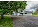 A large detached garage featuring a gray door, adjacent to a spacious asphalt parking area and a smaller garage at 8944 W 21St St, Indianapolis, IN 46234