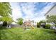 Spacious backyard showcasing a play structure, green lawn, and privacy fence, providing an ideal setting for Gathering enjoyment at 8970 Buttercup Ct, Noblesville, IN 46060