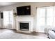 Cozy living room features a fireplace with white mantle, large windows, and hardwood floors at 8970 Buttercup Ct, Noblesville, IN 46060