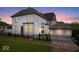 Dusk view of a white two story home with a fenced yard and detached garage at 925 S State Ave, Indianapolis, IN 46203