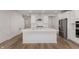 Modern white kitchen with stainless steel appliances, large island, and wood floors at 9767 Behner Dr, Fishers, IN 46250