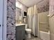 This bathroom has floral wallpaper, a gray sink cabinet, and a shower-tub combo at 100 Lincoln St, Plainfield, IN 46168