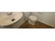 Compact bathroom featuring a pedestal sink, efficient toilet, and wood-look flooring, offering functionality in a small space at 10126 Redwood Peak Ln, Indianapolis, IN 46259