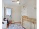 Cozy bedroom features a crib, window with curtains, and a ceiling fan at 1021 Harlan St, Indianapolis, IN 46203