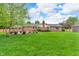 Large backyard featuring a brick home, lush green grass, and a patio at 10559 Rolling Springs Dr, Indianapolis, IN 46234