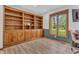 Office with custom wood built-in shelving, cabinets, luxury vinyl plank flooring, and large window at 10559 Rolling Springs Dr, Indianapolis, IN 46234