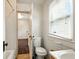 Bright bathroom features a toilet, window with blinds and a door to another room at 1235 N Grant Ave, Indianapolis, IN 46201