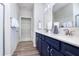Well-lit bathroom with dual sinks, quartz countertops, dark wood cabinetry, and a view into the walk-in closet at 13324 Roundtop Rd, Noblesville, IN 46060