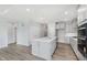 Open-concept kitchen featuring gray cabinets, large island, stainless steel appliances, and modern hardwood floors at 13324 Roundtop Rd, Noblesville, IN 46060