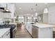 Well-equipped kitchen with stainless appliances, white cabinets, central island and views into the living room at 13324 Roundtop Rd, Noblesville, IN 46060