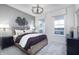 Comfortable bedroom featuring a decorative chandelier, neutral colored walls, and large windows overlooking the lake at 13355 Seven Springs Ln, Noblesville, IN 46060