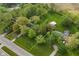 Aerial view outlining land lot with green grass, a house, and a metal building surrounded by bright green trees at 1425 E Us Highway 40, Clayton, IN 46118