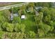 Aerial view of land lot surrounded by green trees, a house, and a metal building with bright green grass at 1425 E Us Highway 40, Clayton, IN 46118