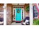 Inviting front porch featuring a bright turquoise door, black wicker furniture, and decorative plants at 18247 Kinder Oak Dr, Noblesville, IN 46062