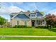 Beautiful two-story home with a manicured lawn, blue siding and brick accents, located on a sunny street at 18820 Wychwood Pl, Noblesville, IN 46062