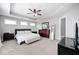 Serene bedroom with neutral tones, tray ceiling, plush carpet, and ample natural light from multiple windows at 18820 Wychwood Pl, Noblesville, IN 46062