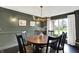 Dining room with olive-green walls, modern chandelier, dark furniture, and natural light at 1933 S 825 E, Zionsville, IN 46077