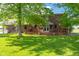 A lush green backyard with a stained wooden deck, brick home, and mature trees at 2221 W County Road 500 N, Danville, IN 46122