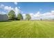 Expansive green lawn featuring mature trees, a tan outbuilding, and a house in the background at 2221 W County Road 500 N, Danville, IN 46122