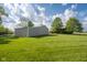 Expansive backyard with lush green grass leading to a tan outbuilding and home in the distance at 2221 W County Road 500 N, Danville, IN 46122