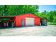 Red outbuilding with garage door and covered areas for equipment storage on a gravel lot surrounded by trees at 2240 Bill Smith Rd, Martinsville, IN 46151