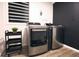 Modern laundry room with front-load washer and dryer, and a stylish black rolling cart at 3401 W Kessler Blvd N Dr, Indianapolis, IN 46222