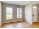 Bright living room features wood floors, two windows and white door with black hardware at 4075 Persian St, Greenwood, IN 46143