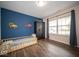 Bright bedroom with blue accent wall, wood floors, and toddler bed at 505 Shallowroot Ln, Sheridan, IN 46069