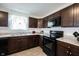 Efficient kitchen with abundant dark-wood cabinets, neutral countertops and black appliances at 509 Tulip Tree Dr, Lapel, IN 46051