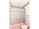 Retro bathroom showcasing a pink bathtub and toilet, complemented by floral wallpaper and tiled walls at 5101 Dickson Rd, Indianapolis, IN 46226