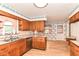 Traditional kitchen with wood cabinets, a stainless steel dishwasher, and breakfast area with floral wallpaper at 5101 Dickson Rd, Indianapolis, IN 46226
