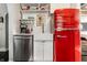 Bright kitchen featuring white cabinetry, a stainless steel dishwasher, a farmhouse sink, and a retro red refrigerator at 5241 Guilford Ave, Indianapolis, IN 46220