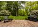 Lush backyard setting with a rocking chair and mature trees creates a private retreat at 5800 Lawrence Dr, Indianapolis, IN 46226